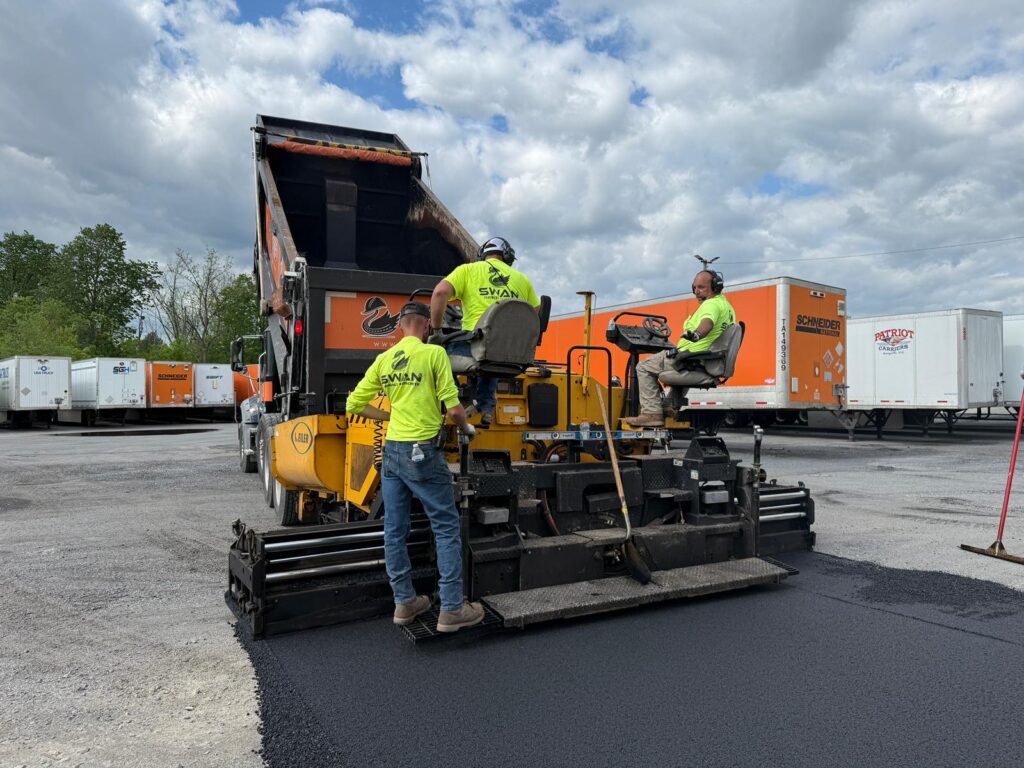 Crew operating asphalt paving equipment during a patch paving project at a commercial lot.