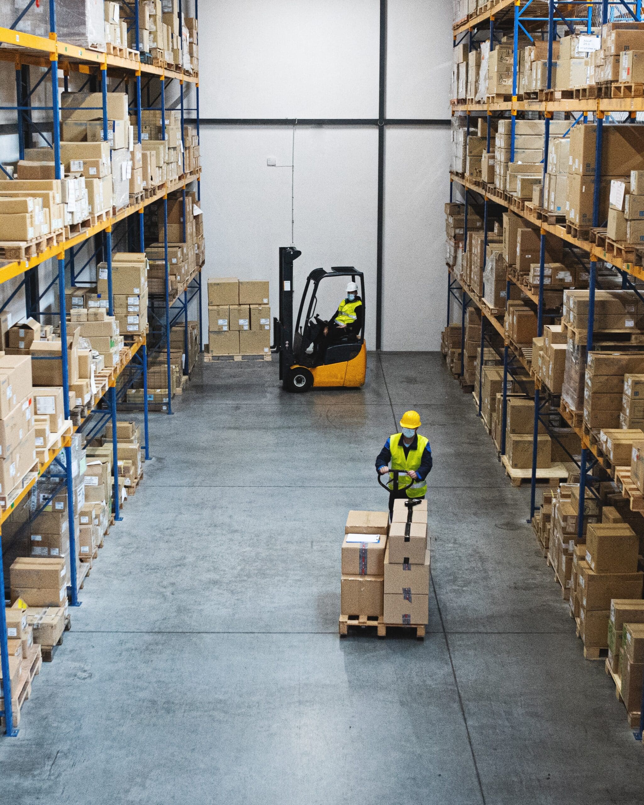 Worker operating pallet jack in warehouse with sealed concrete expansion joints.
