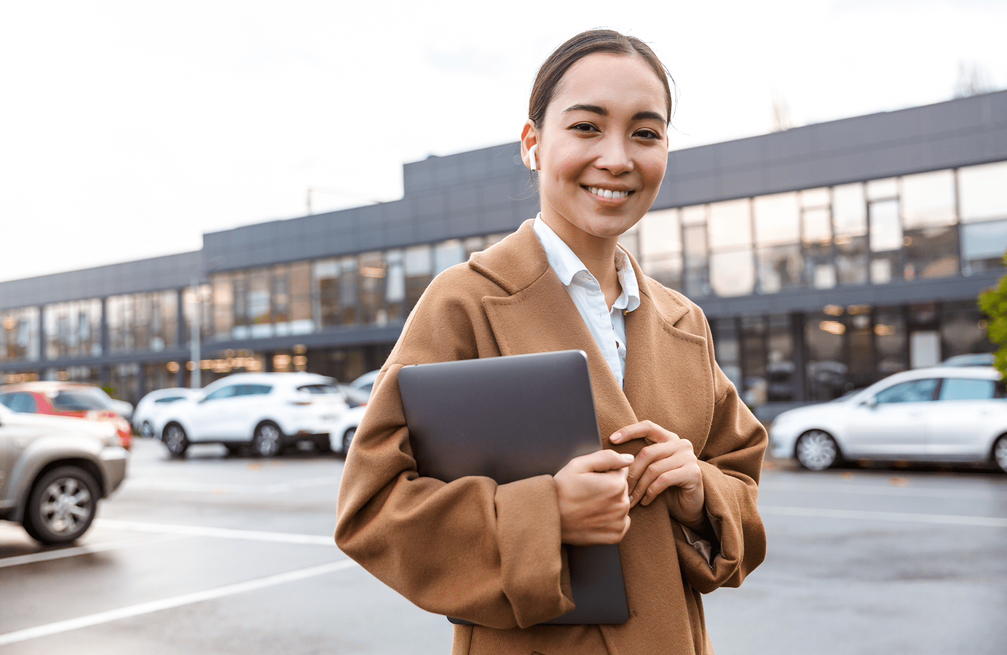 Property manager holding tablet in parking lot, documenting pavement condition and site observations.